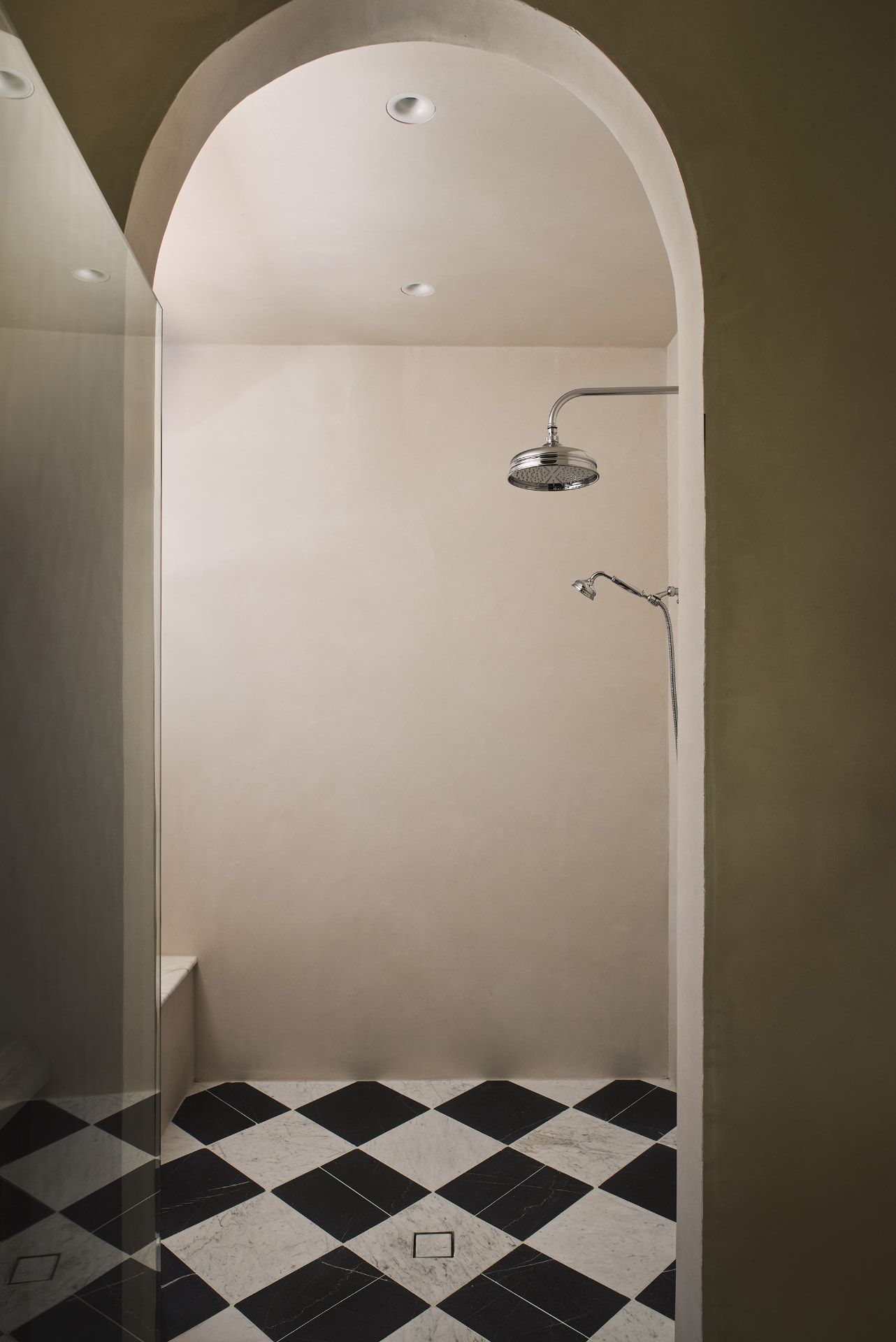 Arched walk-in shower with polished plaster walls and checkered marble floor